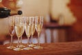 Unrecognizable male filling wineglass with champagne while standing on banquet tabl