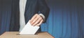 Man Voter Putting Ballot Into Voting box. Democracy Freedom Concept Near Blue Wall