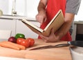 Unrecognizable man in apron at kitchen following recipe book healthy cooking Royalty Free Stock Photo