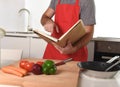 Unrecognizable man in apron at kitchen following recipe book healthy cooking Royalty Free Stock Photo