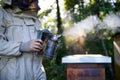 Unrecognizable man beekeeper working in apiary, using bee smoker. Royalty Free Stock Photo