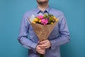 Unrecognizable man in blue hirt holding flowers as gift for his mother