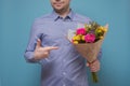 Unrecognizable man in blue shirt holding flowers as gift for his mother or girlfriend on birthday.