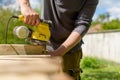 Unrecognizable man in the garden sanding wooden planks. DIY home improvement, restoration, carpentry concept. Royalty Free Stock Photo