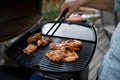 Unrecognizable man grilling meat, ribs and wings, on grill during family summer garden party, close-up