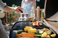 Unrecognizable man grilling ribs and vegetable on grill during family summer garden party, close-up Royalty Free Stock Photo