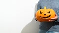 An unrecognizable man holds a carved Halloween pumpkin in front of him. Crop portrait Man in a blue sweater with an