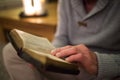 Unrecognizable man at home reading Bible, burning candles behind Royalty Free Stock Photo