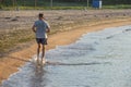 Unrecognizable man jogs on the empty tropical beach and splashes seawater. Man is running on tropical beach