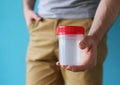 Man holding an empty human sperm sample container, suggesting readiness for a medical test or fertility assessment Royalty Free Stock Photo