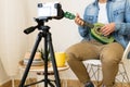 Unrecognizable man recording himself while playing on a green ukulele in a modern studio Royalty Free Stock Photo