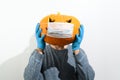 An unrecognizable man in rubber gloves holds a Halloween pumpkin in a medical mask in front of his face. Royalty Free Stock Photo