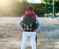 Unrecognizable man wearing a backpack carrying a drone, a tripod and a cap