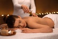 Massage therapist pouring oil on young woman back Royalty Free Stock Photo