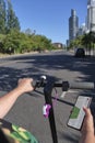 Unrecognizable mature woman looking at a map on her phone, electric kick scooter