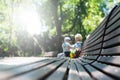 Unrecognizable mom and little son sitting on bench in city park. Spending time together with children outdoors Royalty Free Stock Photo