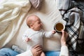 Unrecognizable mother with newborn baby son lying on bed