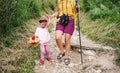 Unrecognizable mother with small crying daughter hiking outdoors in summer nature.