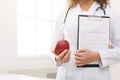 Unrecognizable nutritionist holding apple and diet plan in office Royalty Free Stock Photo