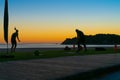 People on beach at Mount Maunganui at sunrise in silhouette doing morning fitnes exercise and walking by