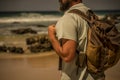 Unrecognizable people caucasian man with beard and backpack enjoying the outdoor nature place with beach and sea in background - Royalty Free Stock Photo