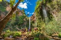 Unrecognizable people enjoy waterfall descent using ropes