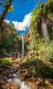 Unrecognizable people enjoy waterfall descent using ropes