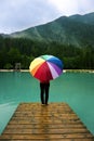 Person with colorful rainbow umbrella standing in the rain