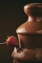 Unrecognizable person dipping strawberry into chocolate