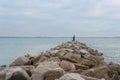 Unrecognizable person fishing from rocky pier on overcast weather