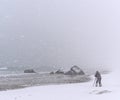 Unrecognizable person photographing a rock on the beach during a windy snowstorm