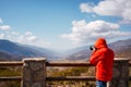 Unrecognizable photographer wearing red jacket taking photos of mountains. copy space