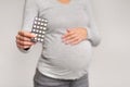 Unrecognizable Pregnant Girl Showing Pills Blister Pack Standing In Studio