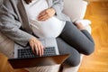 Unrecognizable pregnant woman relaxing on sofa and using laptop Royalty Free Stock Photo