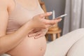 Unrecognizable pregnant woman sitting in bed wearing beige top using mobile phone typing messages browsing internet, holding smart Royalty Free Stock Photo