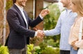 Unrecognizable real estate broker giving house key and shaking hands with new home owners near their property Royalty Free Stock Photo