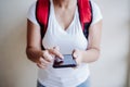 Unrecognizable rider woman wearing red backpack delivering food, checking order with smart phone while standing on street in city Royalty Free Stock Photo