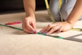 Unrecognizable woman is measuring fabric using rules and measuring tape