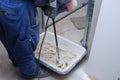 Unrecognizable worker preparing tile adhesive mortar with a hand mixer.