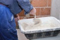 Unrecognizable senior constructor worker preparing tile adhesive mortar.
