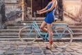 Unrecognizable woman in blue dress on bicycle