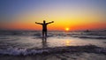 Unrecognizable silhouette walk out of ocean sunset water with hands wide open Royalty Free Stock Photo