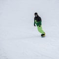 Unrecognizable snowboarder skiing in bright suit, protective glasses mask on the slope. Winter sport, snowboard, leisure