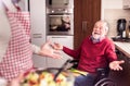 Son and senior father in wheelchair cooking in the kitchen. Royalty Free Stock Photo