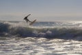 Unrecognizable surfer jumping over a wave, silhouetted against the sky at golden hour Royalty Free Stock Photo