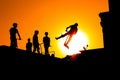 Teenager silhouette showing high jump tricks on scooter against orange sky Royalty Free Stock Photo