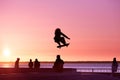 Unrecognizable teenage boy silhouette showing high jump tricks on scooter against Royalty Free Stock Photo