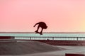 Unrecognizable teenage boy silhouette showing high jump tricks on scooter against Royalty Free Stock Photo