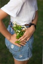 Unrecognizable teenager girl holds a small bouquet of daisies near the back pocket of denim shorts Royalty Free Stock Photo