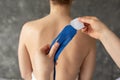 Unrecognizable therapist doctor applying blue kinesio tapes on back of woman patient, removing white film. Kinesiology.